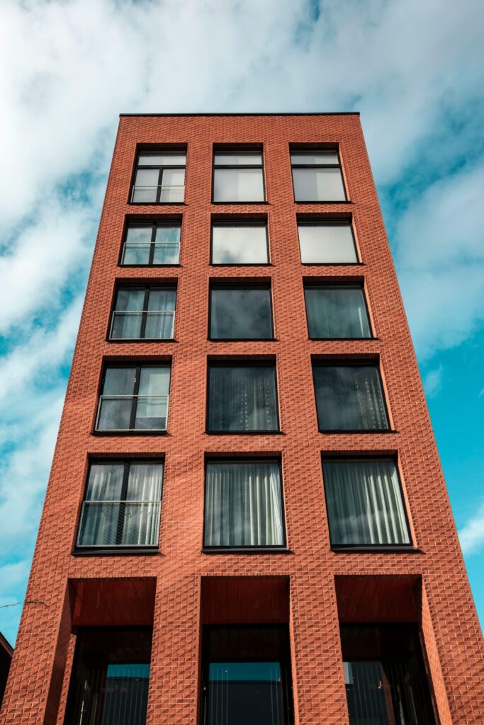 pexels-photo-1031593-1031593 Red-brick modern building against a vibrant blue sky and clouds.