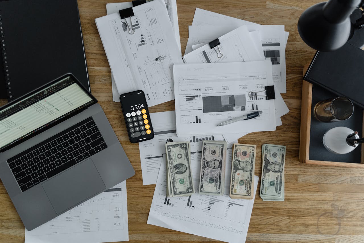 home-img Overhead view of financial documents, cash, and technology on a wooden desk.