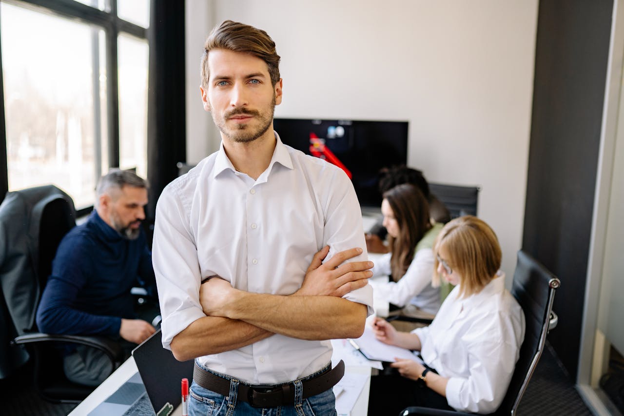 Businessman stands confidently with team in a modern office environment.